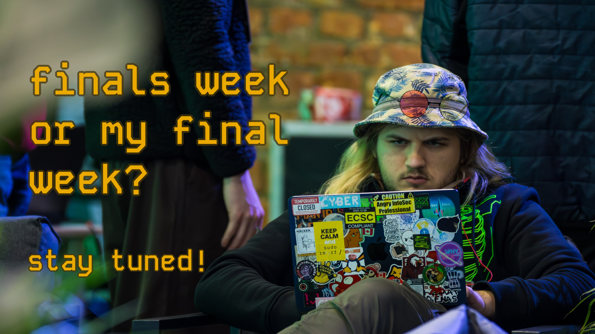 Rihards Kauliņš, saraucis uzacis, lieto ar uzlīmēm aplīmētu klēpjdatoru, sēžot krēslā. Pa kreisi uzraksts "finals week or my final week? stay tuned!".